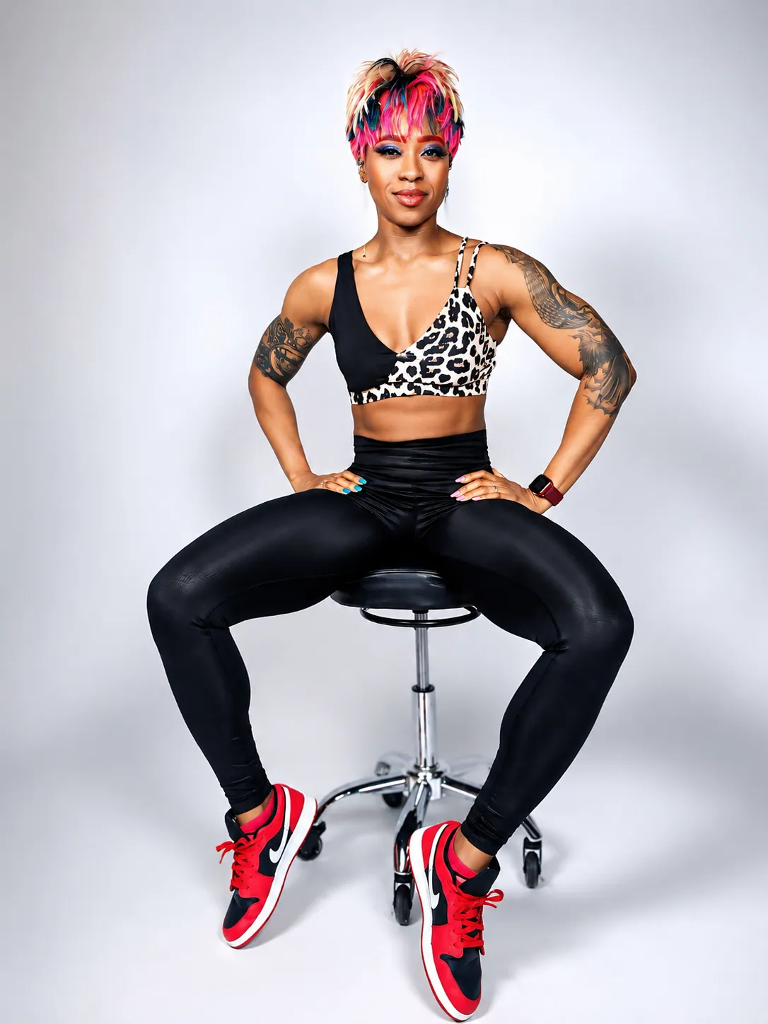Coach Roxy seated on a stool in workout gear, hands on hips