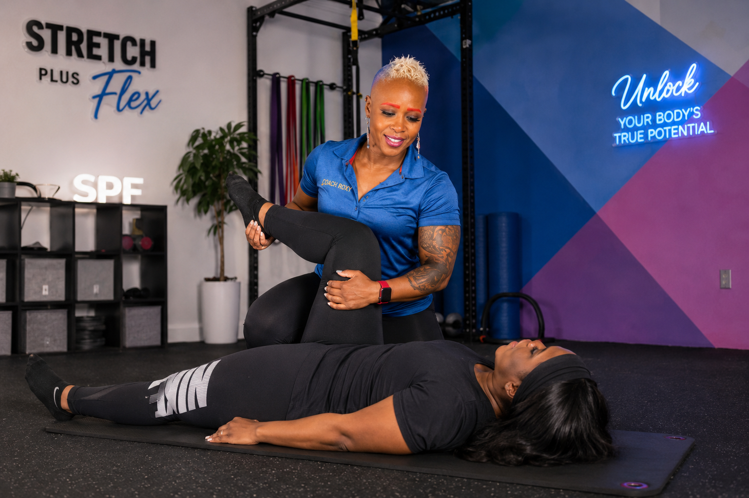 Coach Roxy guiding a client through an assisted hamstring stretch on a mat at StretchPlusFlex in Great Neck Plaza